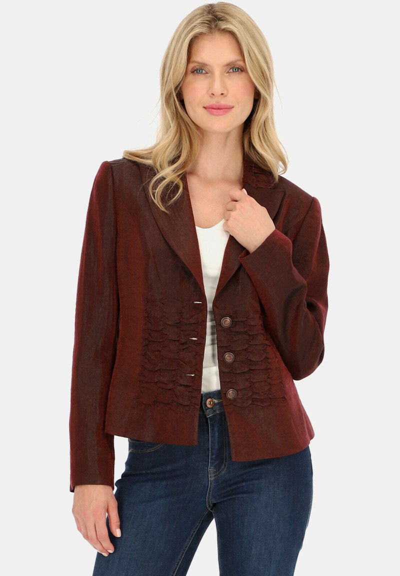 Bordowa, dopasowana kurtka z teksturowanym przodem z falbankami, z wyłogami oraz trzema guzikami z przodu. Nosi się ją na białej bluzce.