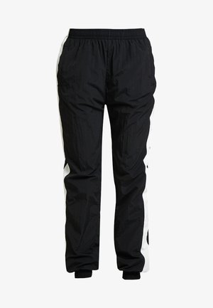 Czarne spodnie dresowe z długim stendem, z białymi panelami po bokach i lekką, pogniecioną teksturą. Rękawy są elastyczne dla lepszego dopasowania.