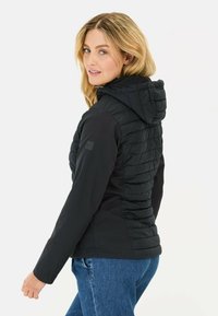 Zwarte pufferjack met capuchon; beschikt over gequiltte secties, een glad lichaam en duurzame stof. Zichtbaar logo op de mouw.