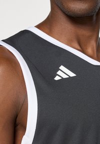 Zwarte basketbaltrui met witte accenten en schouderdetails; voorzien van het Adidas-logo in het wit aan de linkerkant, gemaakt van ademend materiaal.