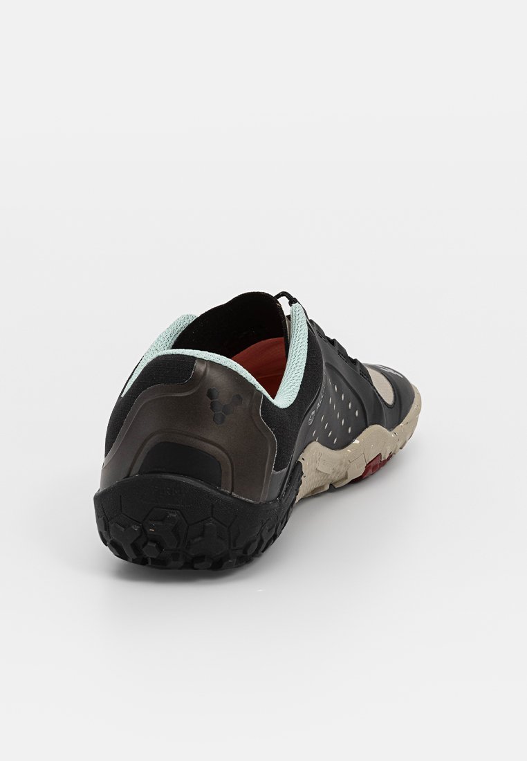Zapatilla deportiva negra con una suela de goma texturizada, un cuello de malla azul claro y detalles perforados en la parte superior para mayor transpirabilidad.