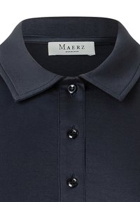 Mörk marinblå polo med klassisk krage, fem knappar fram och en jämn yta. Etiketten visar "Maerz Muenchen."