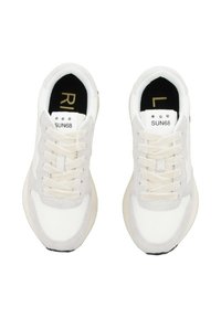 Witte sneakers met grijze suède accenten, voorzien van platte veters, een zwarte binnenzool en merknaam op de tong en zijkanten.