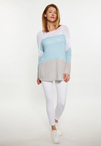 Maglione lavorato a maglia in tonalità pastello di bianco, azzurro chiaro e beige, con una vestibilità ampia e maniche larghe, abbinato a pantaloni skinny bianchi.