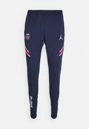 Pantaloni sportivi blu navy con i loghi di Paris Saint-Germain e Jordan, strisce rosse e bianche sulle cosce e scritta "PARIS" sulla parte bassa della gamba.
