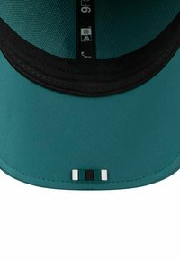 Teal cap with a black brim, featuring a textured interior. Notable details include a multi-colored accent on the front panel.