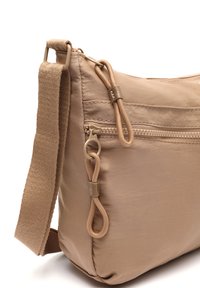 Bežová nylónová crossbody taška s textúrovanou tkaninou, so zipsom a tkaným ramenným popruhom. Obsahuje dekoračný zipsový prídavok a kovové akcenty.