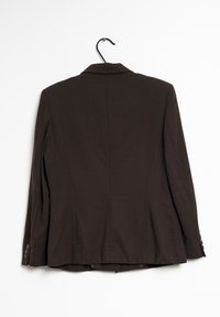 Blazer en cuir marron avec un col étroit, manches longues, une fente arrière simple et des accents de boutons sur chaque poignet. Accroché à un crochet noir.