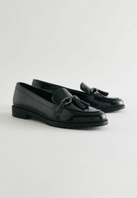 Schwarze Lackleder-Lederschuhe mit Quasten-Detail und niedrigem, gestapeltem Absatz, mit einer strukturierten Oberfläche und glatten Kanten. Robuste Gummisohle.