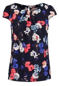 Blommig blus i marinblått med korta ärmar. Har livliga röda, blå och vita blommor. Inkluderar en plisserad detalj vid halslinningen.