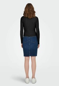 Top nero a maniche lunghe abbinato a una gonna di jeans blu attillata. La gonna presenta due tasche posteriori e un orlo sopra il ginocchio. Sneakers bianche.