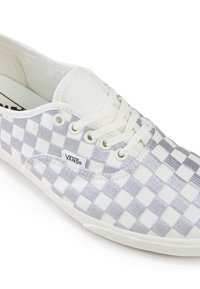 Bílé tenisky s šedým kostkovaným vzorem, plátěný materiál, šněrovací design a gumová podrážka. Obsahují branding Vans na boku.