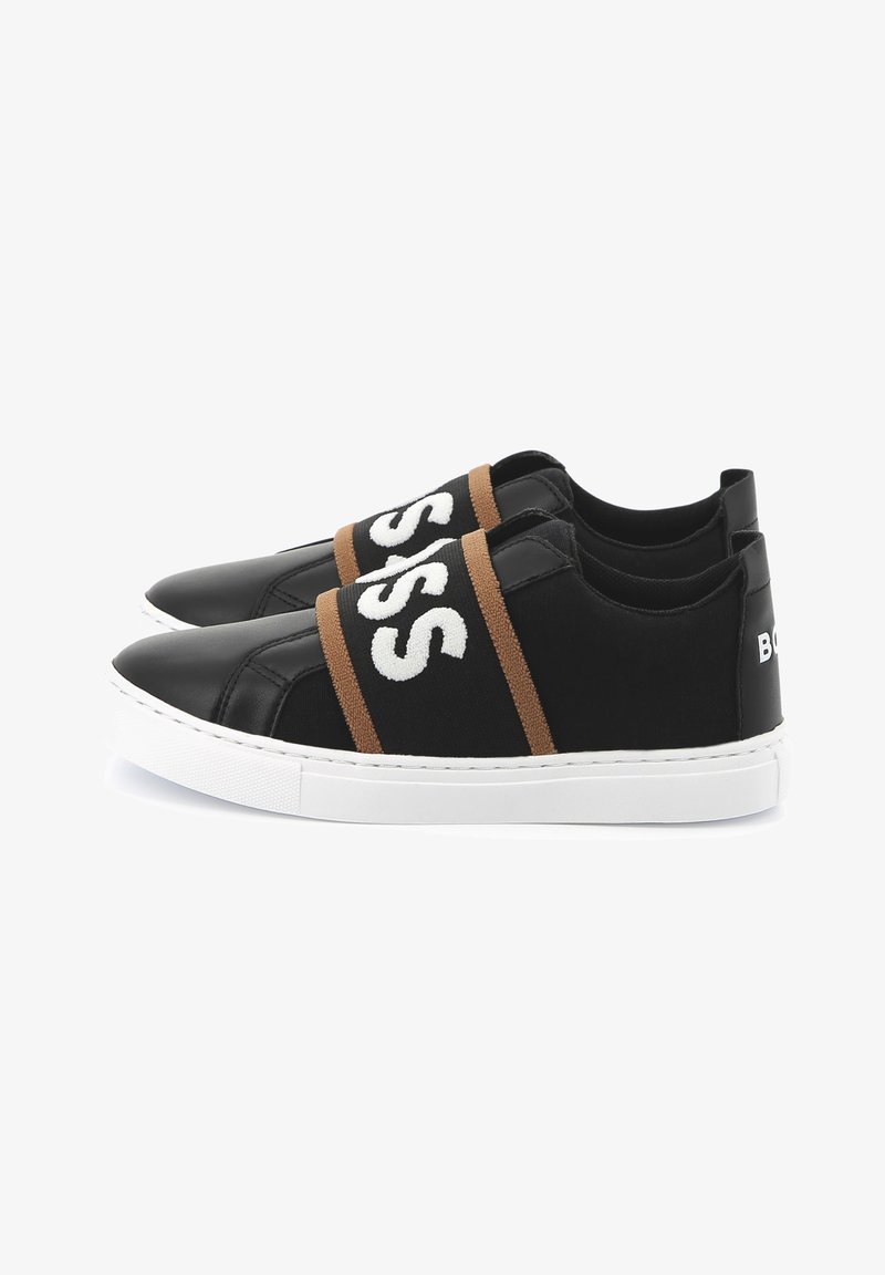 Sapatilhas pretas com cintas elásticas, apresentando texto branco, detalhes em castanho e uma sola de borracha branca. Materiais de couro liso e tecido.