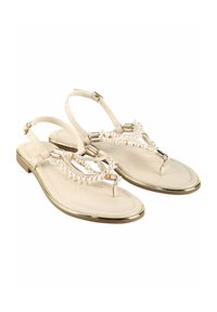 Sandale avec une tige en simili cuir beige, ornée d'accents en perles et de quincaillerie dorée, conçue avec une semelle plate et une silhouette à lanière T.