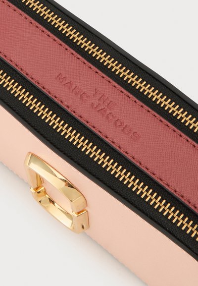 Ροζ και βουργουνδί πορτοφόλι Marc Jacobs με φερμουάρ, χρυσούς μεταλλικούς λεπτομέρειες και μαύρη επένδυση.