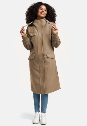 Beige long coat with a high collar, two front pockets, and textured knit sleeves, paired with blue jeans and white sneakers.