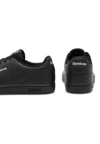 Mustad mustad Reebok jalanijad, mille suhteline sünteetiline ülemine, ümar nina, paeladise disain ja logo aktsendid külgedel ja kandadel. Lame kummitald.