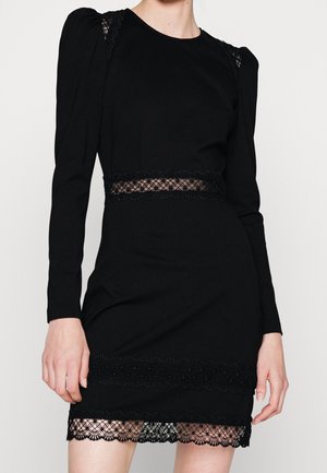 Robe noire à manches longues avec inserts en dentelle à la taille, aux épaules et à l'ourlet, présentant une silhouette ajustée et un détail d'épaule bouffante.