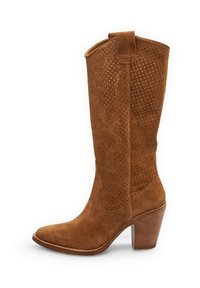 Bota de vaquero de ante marrón con detalles perforados, puntera puntiaguda y tacón apilado. La textura suave complementa el diseño general.