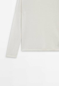 Maglietta a maniche lunghe in morbido tessuto crema, con texture liscia e orlo dritto, completata da polsini abbinati per un look uniforme.