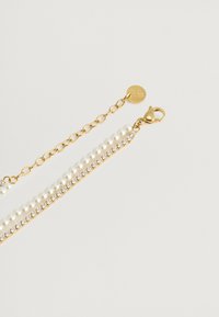 Bracciale in oro con due file di perle bianche e una fila di strass trasparenti, con chiusura a moschettone e charm con logo.