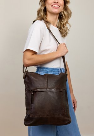 Braune Leder-Schultertasche mit glatter Textur, ausgestattet mit einer vorderen Reißverschlusstasche und einem verstellbaren Gurt. Runde Form, lässiges Design.