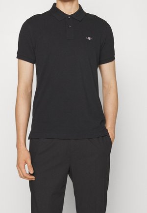 Czarna koszulka polo z mieszanki bawełny, z trzema guzikami, krótkimi rękawami i małym logo na lewej piersi. Gładka tekstura.