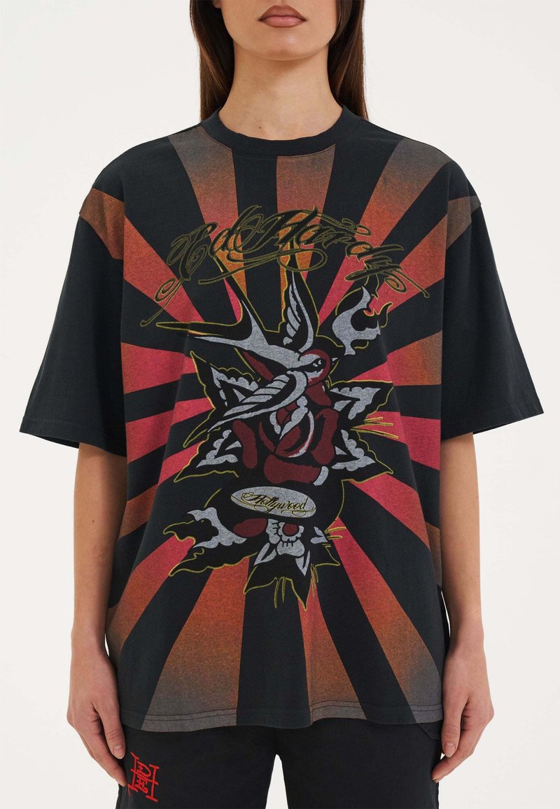 Zwart oversized T-shirt met een gedurfde rode en oranje zonnestraalpatroon, met een intricaat ontwerp van een roos en vogels in levendige kleuren.