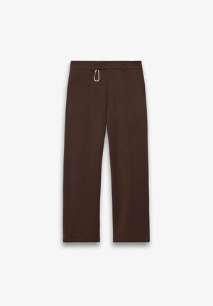 Ciemnobrązowe spodnie o prostych nogawkach z szlufkami na pasek i małą srebrną karabińczykiem przymocowanym do pasa.