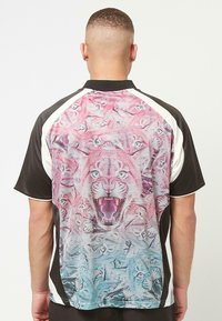 Kurzes Trägershirt mit einem lebhaften rosa und blauen Tiger-Muster auf dem Rücken, schwarzen Seiten und einem weißen Kragen. Glatte Textur.