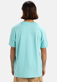 Camiseta de algodón azul claro con cuello redondo y mangas cortas, con una textura suave y un corte relajado. Sin patrones ni acentos visibles.