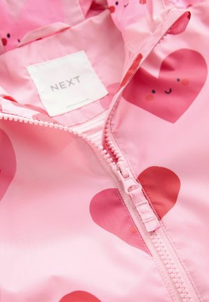 Rozā ūdensnecaurlaidīga jaka ar sirds rakstu, priekšējo rāvējslēdzēju un uzrakstu "NEXT" uz birkas. Gluda tekstūra ar rotaļīgiem akcentiem.