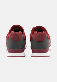 Röda och grå sneakers med en slät läderutveckling, vadderad krage och vita sulor. Har en logotyp präglad på baksidan.