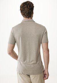 Ljusgrå kortärmad polo skjorta med krage, slät textur och subtila sömmar, tillsammans med ljusa shorts.