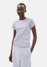 Lichtgrijs geribd t-shirt met korte mouwen en een ronde hals, met een getailleerd ontwerp en subtiele stikdetails. Gecombineerd met bijpassende sweatpants.