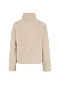 Beżowy polarowy sweter z wysokim kołnierzem, fakturowaną powierzchnią, luźnym krojem i długimi rękawami. Minimalistyczny design, bez widocznego sprzętu ani akcentów.