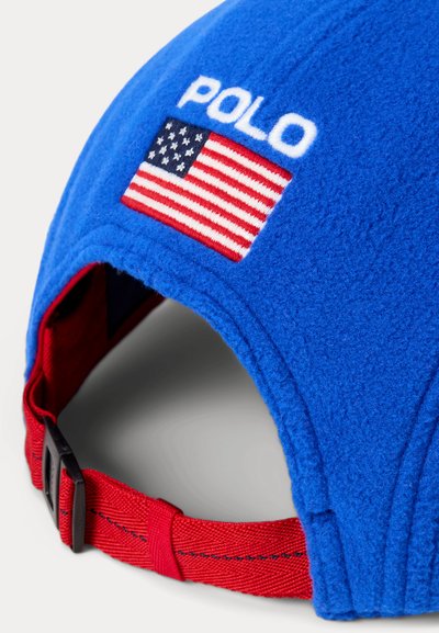Blauer Fleecehut mit rotem verstellbarem Riemen, besticktem "POLO"-Schriftzug und einer Patch der Vereinigten Staaten auf der Rückseite. Weiche Textur.