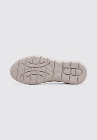 Semelle de chaussure en caoutchouc beige clair avec des motifs de grip texturés et un logo, présentant des lignes de tread définies et une section de bout arrondie.
