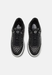 Sneaker in pelle nera con dettagli in occhioletto argentato, lacci neri e suole bianche, con il logo Michael Kors sulla linguetta.