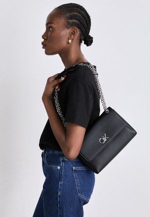 Black leather shoulder bag with a silver chain strap, featuring a textured finish and a logo accent on the front.