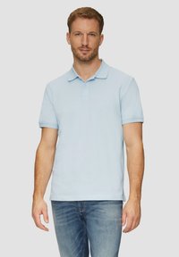 Jasnoniebieska koszulka polo z kołnierzykiem, krótkim rękawem i zapięciem na dwa guziki, wykonana z miękkiej bawełny, w zestawie z dżinsami.