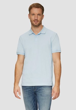 Helles blaues Poloshirt mit Kragen, kurzen Ärmeln und einer Knopfleiste mit zwei Knöpfen, aus weichem Baumwollgewebe, kombiniert mit Jeans.