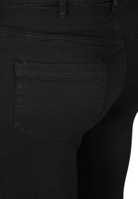 Svarta denimjeans med en bakficka som har en rak söm och en mjuk textur. Tyget verkar lätt och flexibelt.