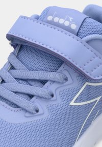 Chaussure de sport violet clair avec tige en mesh, semelle en caoutchouc et système de laçage, dotée d'une sangle au milieu du pied et d'accents texturés.