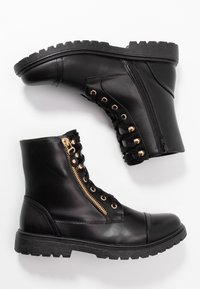 Svarta läderstövlar med texturerad yta, guldfärgade blixtlås, guldfärgade detaljaccents och en robust sulprofil.