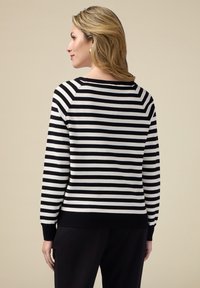 Svartvitt randig tröja med rund halsringning, långa raglanärmar och ribbad nederkant. Mjuk tyg, figursydd design.