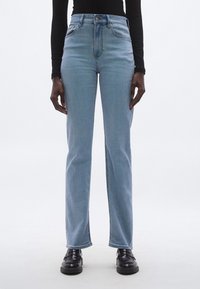 Svijetloplave traperice s visokim strukom i ravnim krojem nogavica, s prednjim džepovima, petljama za remen i suptilnim izblijedjelim teksturom.