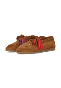 Mocasines de ante marrón con borlas de cuero rojas y moradas, tachuelas doradas en la parte superior y suelas planas de goma sobre un fondo blanco.