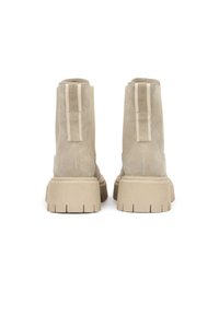 Bottines beige en daim, dotées d'une semelle en caoutchouc épaisse beige, de languettes à l'arrière et d'une texture lisse.