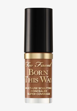 Correcteur sculptant multi-usage Too Faced Born This Way en teinte medium-deep avec un capuchon noir et des lettres dorées.